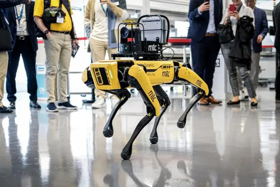 A quadruped robot from MTC's robotics lab walking past visitors